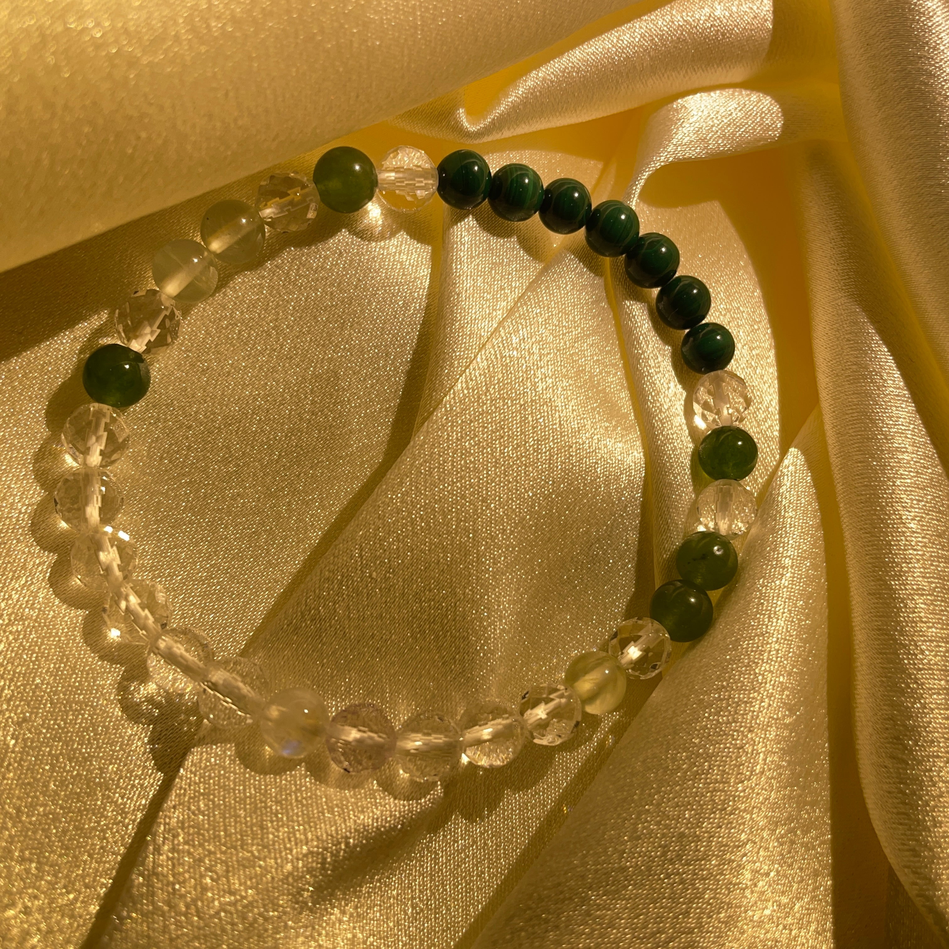 The image showcases a Hetian jade Malachite Faceted Quartz bracelet named "Dance of Blue Moonlight," featuring an emerald green hue shimmering with a unique glow.